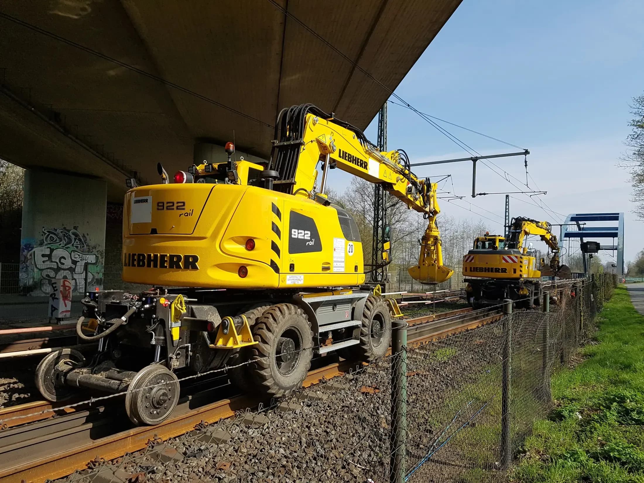 Bahnbaumaschine mit Greifer beim Materialhandling im Gleisbereich